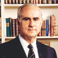 The Honourable Hal Jackman in front of a bookshelf wearing a suit.