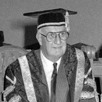 Chancellor John Black Aird in a black and white photograph, seated in his ceremonial robes and mortar board.